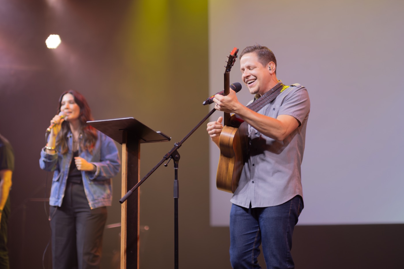 Davi Kirsch tocando violão e sorrindo no palco da Banda Prossigo da Igreja Fonte